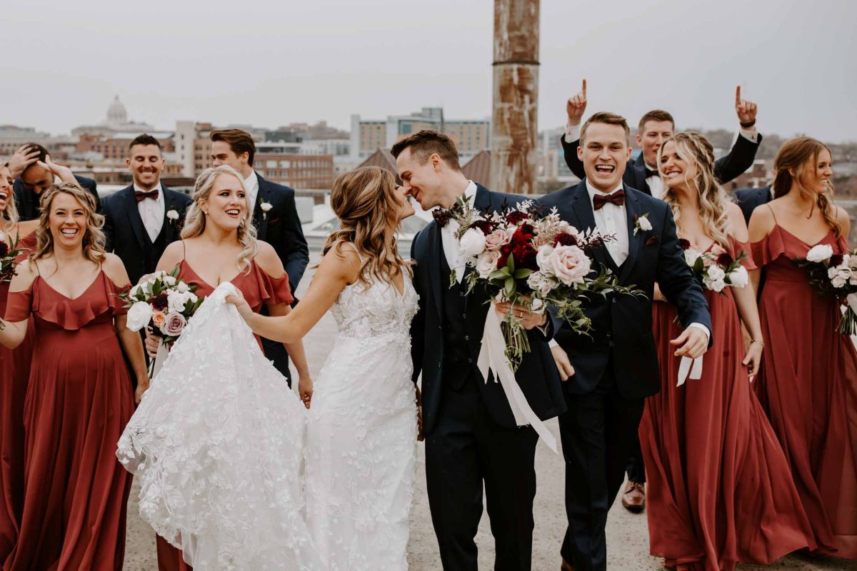 couple kissing and wedding party cheering