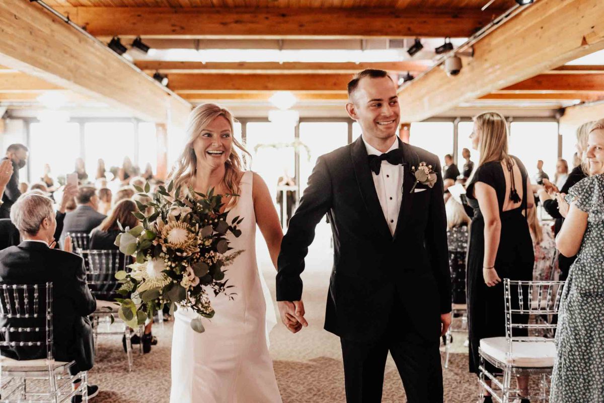 couple holding hands down aisle